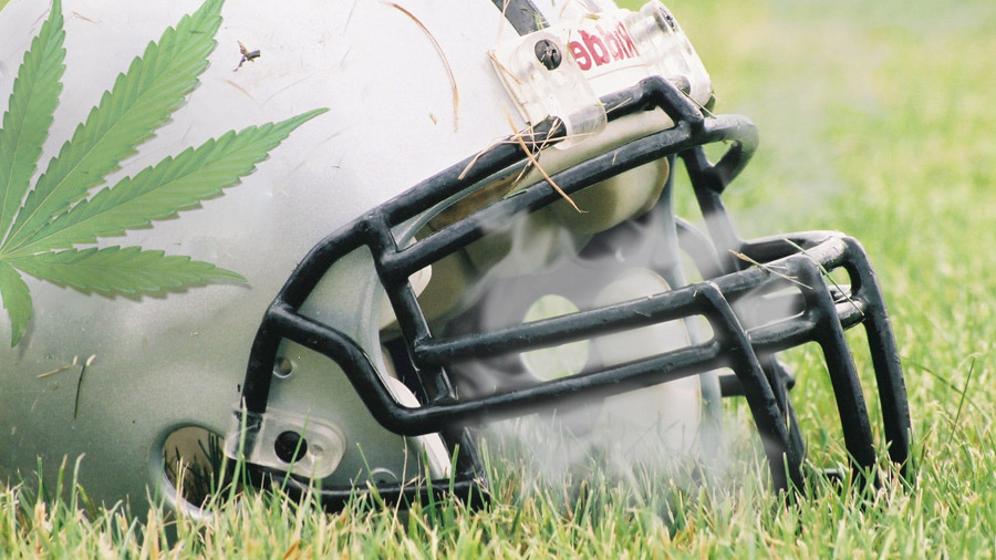 Fotografia em close-up e vista lateral de um capacete de futebol americano de cor branca e com um desenho da folha da maconha e grade preta, sobre um gramado; no interior do capacete pode-se ver uma fotomontagem de fumaça.