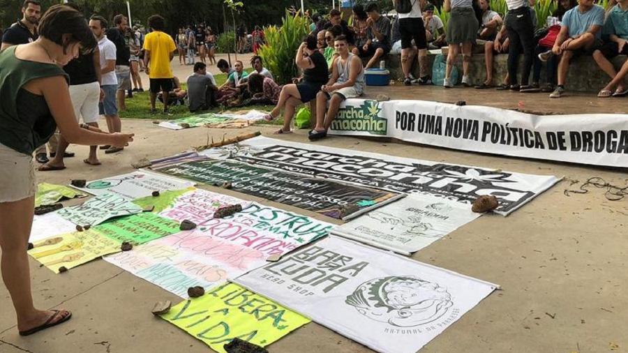 Oficina de cartazes da Marcha da Maconha de João Pessoa, onde várias faixas e cartazes estão no chão do Parque Sólon de Lucena, com vários manifestantes ao fundo.