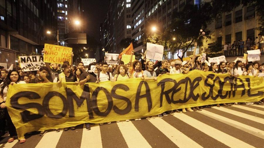 Multidão nas ruas do Rio de Janeiro, levando à frente uma faixa amarela com os dizeres em preto "Somos a rede social", durante as manifestações de junho de 2013.