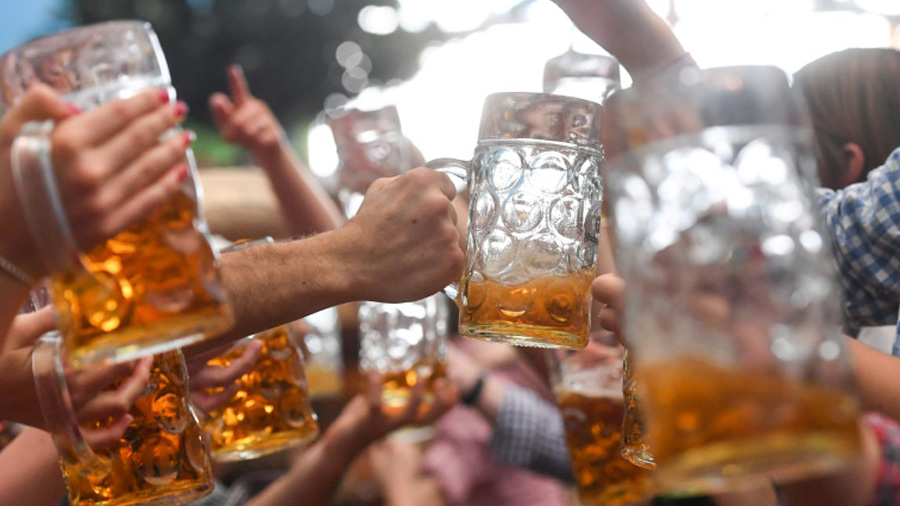 Várias mãos segurando canecas de vidro grandes com cerveja