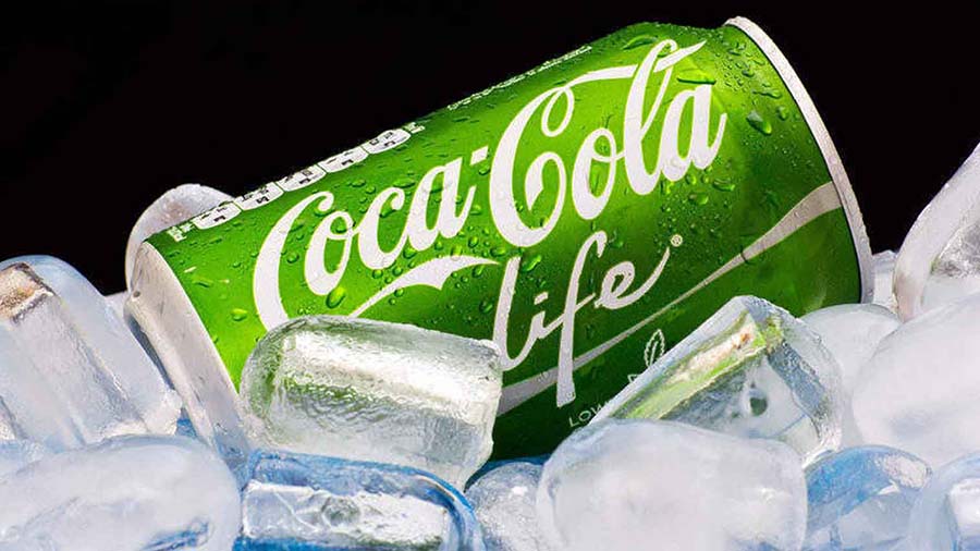 Foto meramente ilustrativa que mostra uma lata da Coca-Cola life (que não contém CBD ou qualquer outro composto da cannabis) sobre pedras de gelo, e um fundo preto.