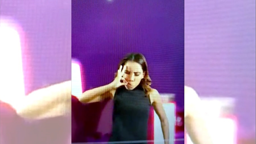 Foto da intérprete de libras, na live da Ludmilla, com a mão junto à boca como quem está fumando um baseado e os olhos fechados e um fundo em tons de roxo. Imagem: reprodução / Youtube.