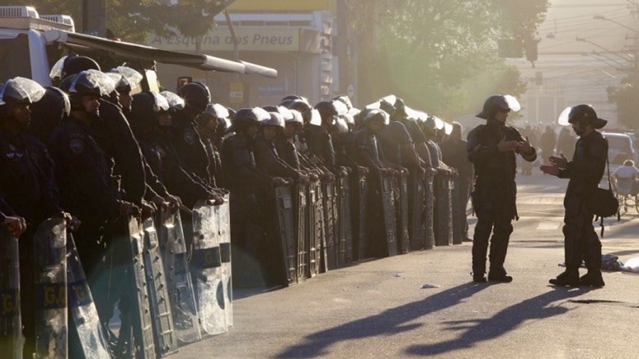 Fotografia em vista diagonal que mostra uma fileira de policiais montados com capacetes e escudos, nas proximidades da praça Princesa Isabel, no centro de São Paulo. Imagem: reprodução / SP Notícias.