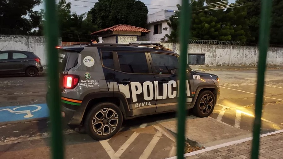 Fotografia tirada atrás de grades verdes que mostra uma viatura da polícia civil do Ceará na rua. Foto: divulgação / MPCE.