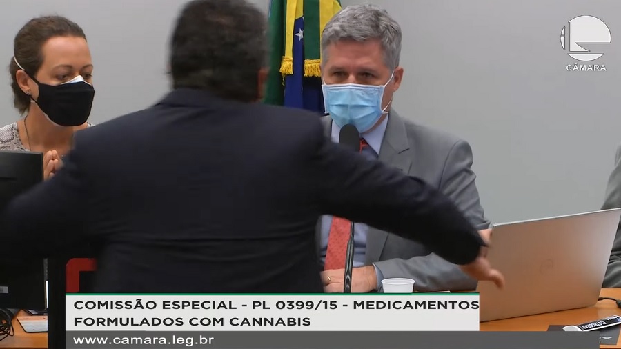 Screenshot da gravação da reunião na Câmara que mostra o deputado Diego Garcia de costas com os braços abertos, no primeiro plano, desfocado, e Paulo Teixeira sentado ao fundo.