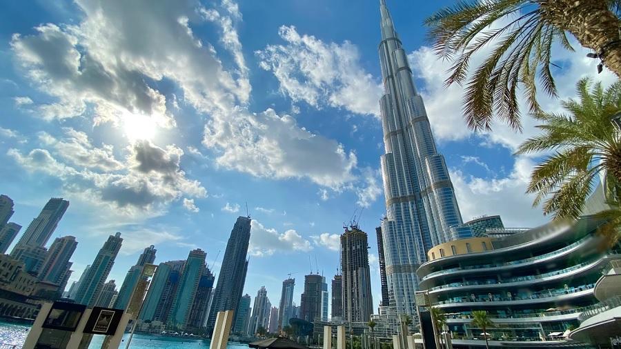 Fotografia, em vista inferior, mostra o prédio Burj Khalifa e os demais edifícios menores ao redor, e o Sol parcialmente encoberto pelas nuvens, em Dubai (Emirados Árabes Unidos). Foto: Unsplash / Wael Hneini.