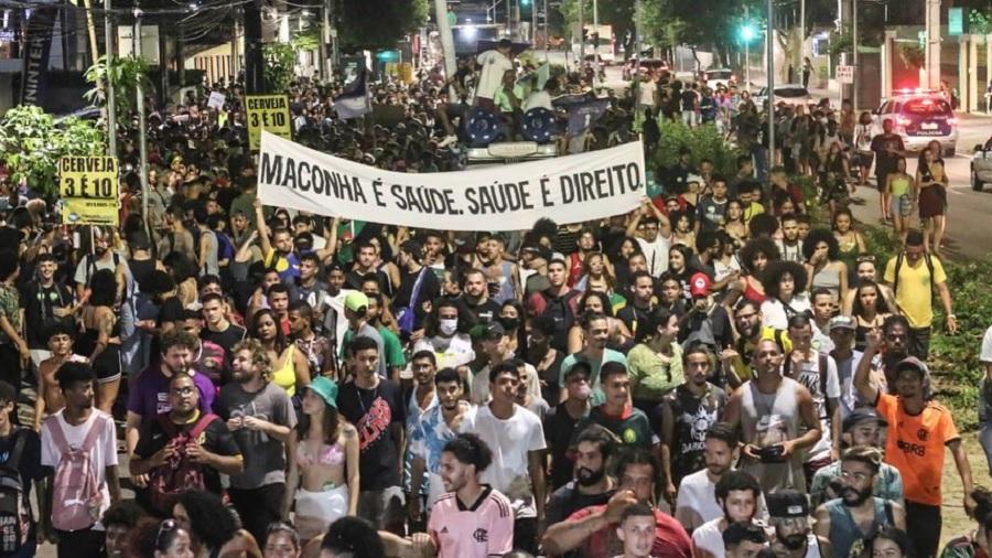 Fotografia mostra uma multidão nas ruas de Pernambuco e uma faixa branca com as palavras "maconha é saúde, saúde é direito", em preto, levantada por manifestantes. Foto: Fran Silva / Marcha da Maconha Recife.