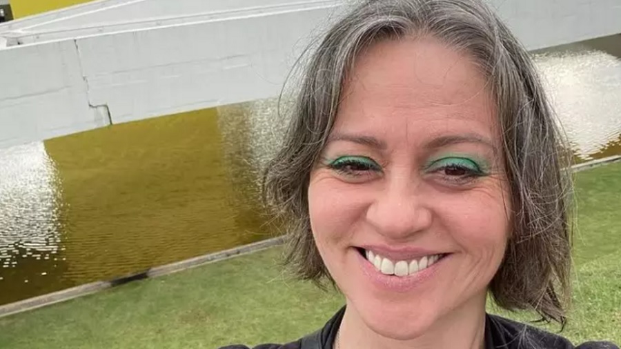 Selfie de Guta Stresser, onde a atriz aparece sorridente com sombra verde nos olhos, à frente de um lago. Imagem: reprodução / gutastresser.