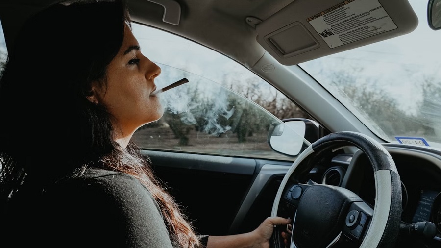 Foto mostra mulher ao volante com um baseado na boca. Imagem: Unsplash / Elsa Olofsson.