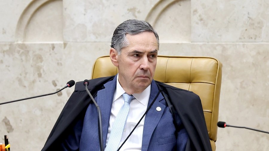 Fotografia mostra o ministro Luís Roberto Barroso vestido com casaco azul, camisa branca e gravata azul-clara, e com a toga sobre os ombros, sentado em sua cadeira no Supremo Tribunal Federal, durante sessão plenária. Imagem: Gustavo Moreno.