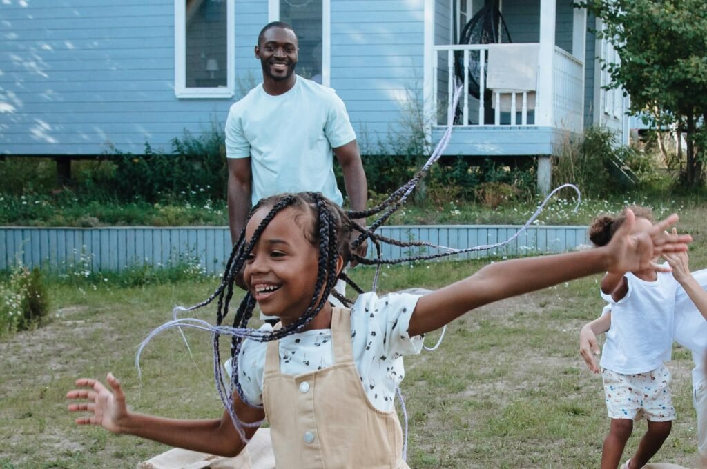 Foto mostra uma família brincando no quintal de uma casa. Imagem: Pexels | Ron Lach.