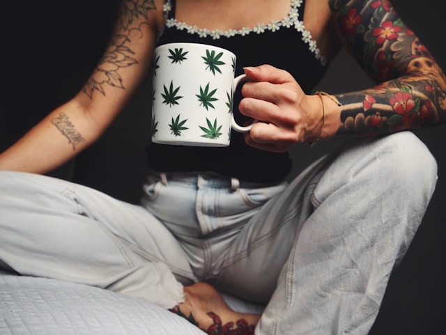 foto mostra mulher segurando uma caneca com folhas de cannabis. Foto High Babe Unsplash