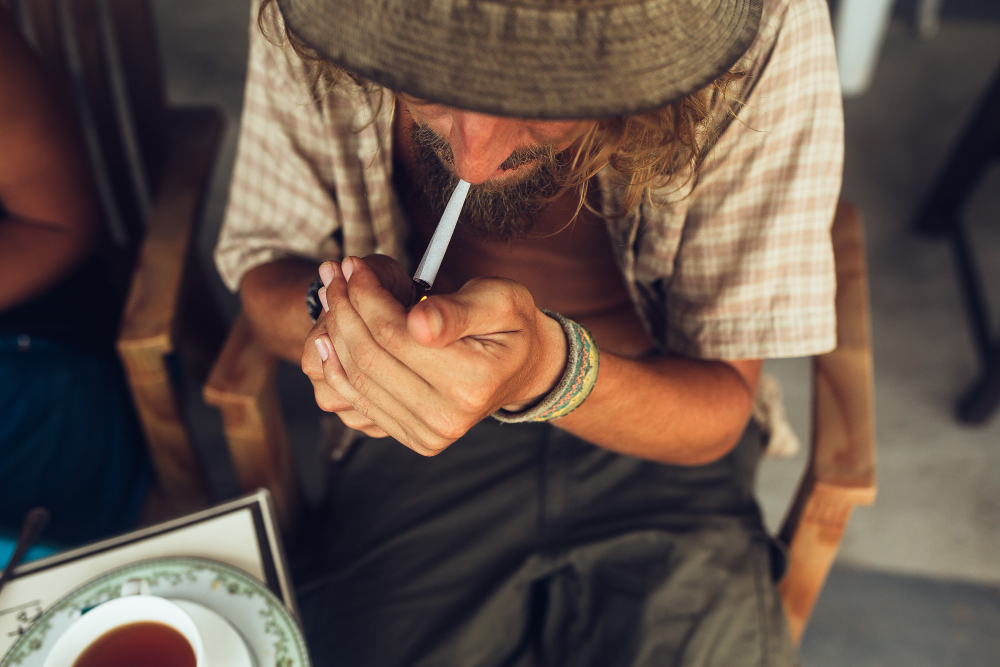 Fotografia mostra vista aérea de homem acendendo um cigarro. Foto: freepik